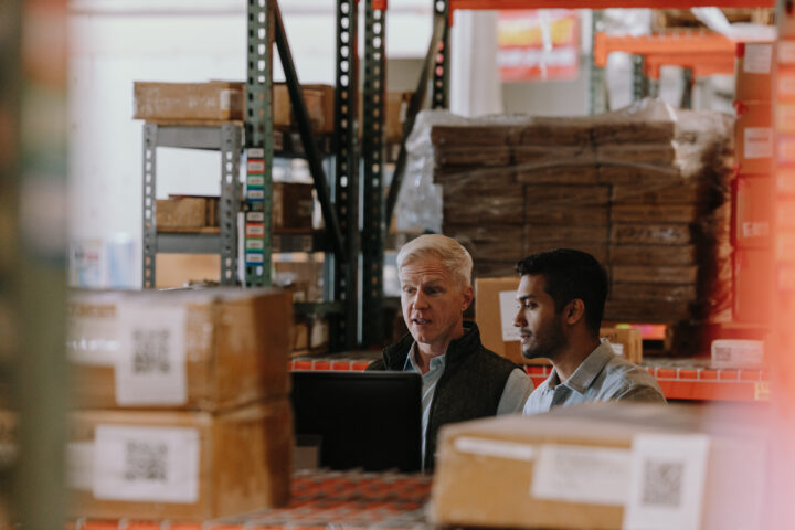 B_CAM_WAREHOUSE_G_0306_R2_SM 2 shippers looking a computer screen in a warehouse